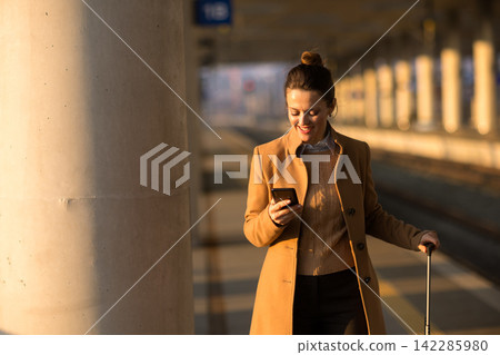Relaxed Female Traveler Checking Phone at Train Platform Relaxed Female Traveler Checking Phone at Train Platform 142285980
