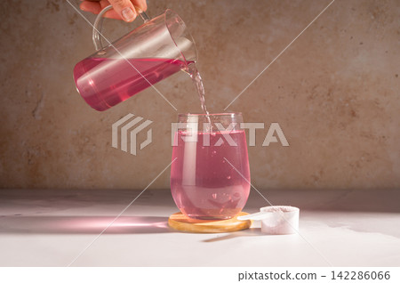 Pink food supplement powder in glass of water. Collagen, protein powder, vitamins. Pink food supplement powder in glass of water. Collagen, protein powder, vitamins. 142286066