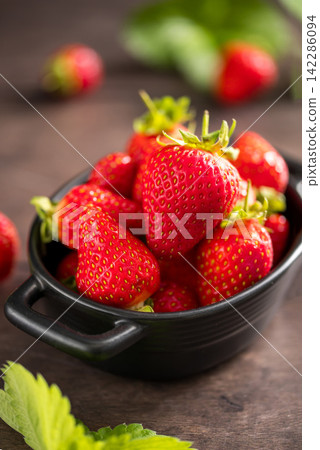 Fresh strawberries in a black bowl, summer fruits. 142286094