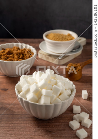 Light brown, dark brown and white sugar cubes in bowls. Different type of sugar Light brown, dark brown and white sugar cubes in bowls. Different type of sugar 142286101