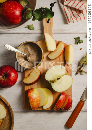Red apples, whole and sliced on a wooden cutting board, lifestyle, top view. Autumn abstract food background. Red apples, whole and sliced on a wooden cutting board, lifestyle, top view. Autumn abstract food background. 142286168