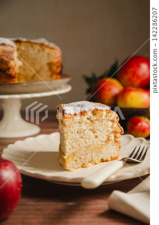 Slice of homemade apple cake with cinnamon, wooden background, lifestyle moody food photo Slice of homemade apple cake with cinnamon, wooden background, lifestyle moody food photo 142286207