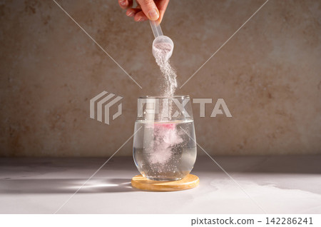 Pouring food supplement powder in glass of water. Collagen, protein powder, vitamins. Pouring food supplement powder in glass of water. Collagen, protein powder, vitamins. 142286241