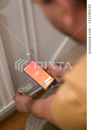 Smartphone connecting to heating radiator. Remote home control system on a smartphone. Smartphone connecting to heating radiator. Remote home control system on a smartphone. 142286242