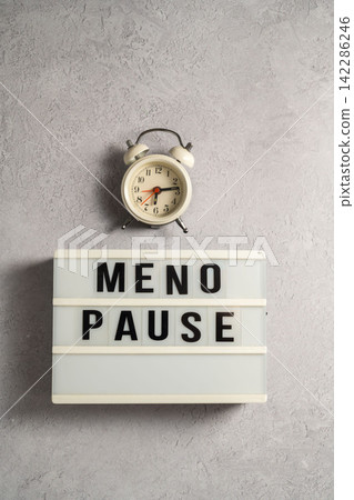 Word Menopause on a light box with alarm clock, flat lay, grey background Word Menopause on a light box with alarm clock, flat lay, grey background 142286246
