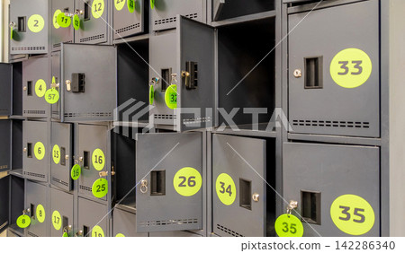 Grey Metal Storage Lockers with Yellow Numbered Stickers and Open Doors Grey Metal Storage Lockers with Yellow Numbered Stickers and Open Doors 142286340