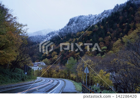 一條蜿蜒的小路穿過秋葉覆蓋的山谷。 142286420