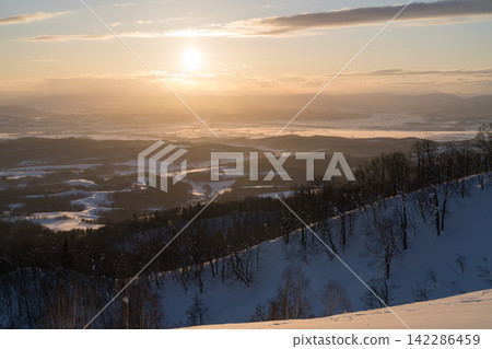 Snow-covered hills illuminated by the soft setting sun Snow-covered hills illuminated by the soft setting sun 142286459