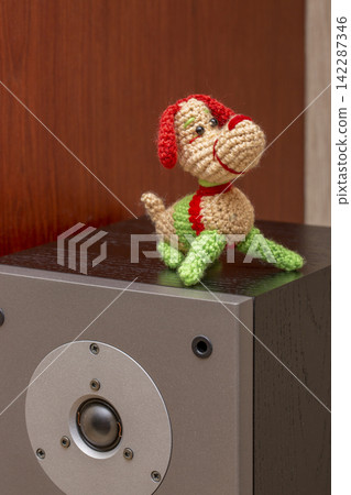 A knitted wool dog stands on a speaker. A knitted wool dog stands on a speaker. 142287346