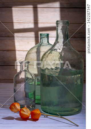 A physalis branch and glass jars on a wooden board background A physalis branch and glass jars on a wooden board background 142287347