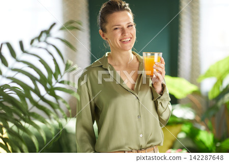 Smiling Woman with Orange Juice and Indoor Plants Smiling Woman with Orange Juice and Indoor Plants 142287648