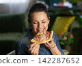 Woman Biting into Delicious Pizza at Home 142287652