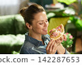 Happy Woman Smelling Fresh Pizza Slice at Home 142287653