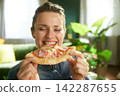 Contented Young Woman Holding a Slice of Pizza 142287655