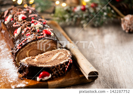 Christmas chocolate yule log cake with festive decorations Christmas chocolate yule log cake with festive decorations 142287752