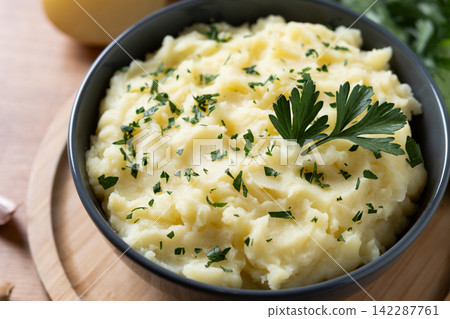 Creamy mashed potatoes with fresh parsley on wooden table Creamy mashed potatoes with fresh parsley on wooden table 142287761