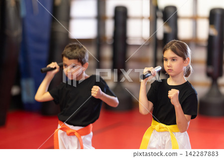 Children holding nunchucks in their hands Children holding nunchucks in their hands 142287883
