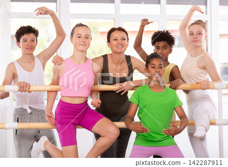 Teenage boys and girls posing at ballet bra with ballet-master in dance studio Teenage boys and girls posing at ballet bra with ballet-master in dance studio 142287911