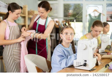 Teen girl child sews during practical lesson at school of young fashion designers Teen girl child sews during practical lesson at school of young fashion designers 142288017