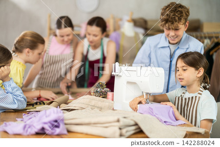 Little girl sewing on machine during hands-on class for school children Little girl sewing on machine during hands-on class for school children 142288024