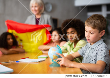 Female teacher showing spanish flag to kids in geography class Female teacher showing spanish flag to kids in geography class 142288066