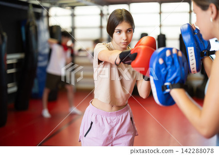 Two teenage girls training in boxing mitts and boxing gloves Two teenage girls training in boxing mitts and boxing gloves 142288078