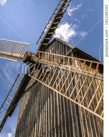 Rustic Wooden Windmill With Sunlit Sails Against A Clear Blue Sky In Countryside Rustic Wooden Windmill With Sunlit Sails Against A Clear Blue Sky In Countryside 142288102