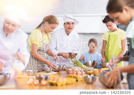 Sociable young chef leading culinary courses to group of tweens Sociable young chef leading culinary courses to group of tweens 142288105