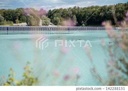 Vertical floating solar panels on the Gilching quarry lake in Bavaria, Germany, beside a gravel and crushing plant, renewable energy infrastructure, industrial landscape and innovative clean Vertical floating solar panels on the Gilching quarry lake in Bavaria, Germany, beside a gravel and crushing plant, renewable energy infrastructure, industrial landscape and innovative clean 142288131