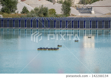 Vertical floating solar panels on the Gilching quarry lake in Bavaria, Germany, beside a gravel and crushing plant, renewable energy infrastructure, industrial landscape and innovative clean 142288134