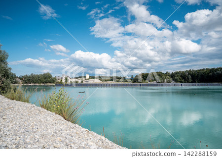 Vertical floating solar panels on the Gilching quarry lake in Bavaria, Germany, beside a gravel and crushing plant, renewable energy infrastructure, industrial landscape and innovative clean Vertical floating solar panels on the Gilching quarry lake in Bavaria, Germany, beside a gravel and crushing plant, renewable energy infrastructure, industrial landscape and innovative clean 142288159