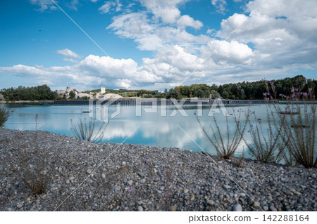 Vertical floating solar panels on the Gilching quarry lake in Bavaria, Germany, beside a gravel and crushing plant, renewable energy infrastructure, industrial landscape and innovative clean Vertical floating solar panels on the Gilching quarry lake in Bavaria, Germany, beside a gravel and crushing plant, renewable energy infrastructure, industrial landscape and innovative clean 142288164