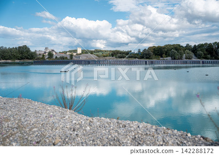 Vertical floating solar panels on the Gilching quarry lake in Bavaria, Germany, beside a gravel and crushing plant, renewable energy infrastructure, industrial landscape and innovative clean Vertical floating solar panels on the Gilching quarry lake in Bavaria, Germany, beside a gravel and crushing plant, renewable energy infrastructure, industrial landscape and innovative clean 142288172
