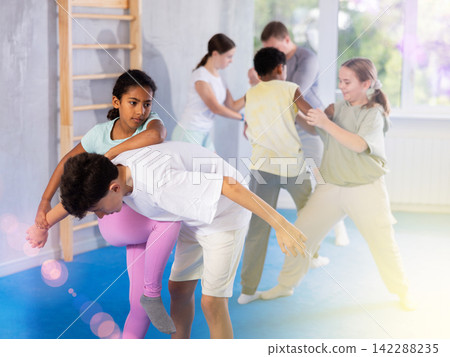 African teenage girl practicing wristlock with elbow and knee blows in sparring with boy African teenage girl practicing wristlock with elbow and knee blows in sparring with boy 142288235