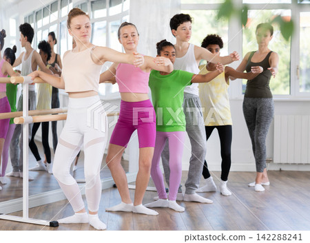 Teen girl mastering demi plie at barre at group ballet class Teen girl mastering demi plie at barre at group ballet class 142288241