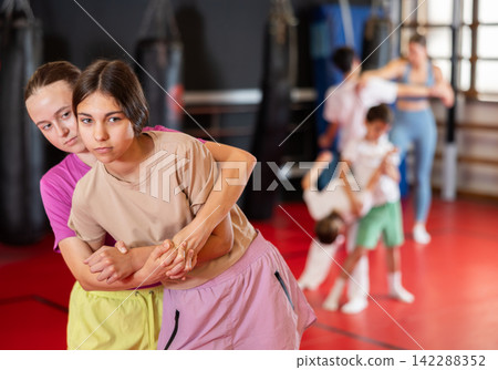 Girls practice self-defense strikes in the gym 142288352