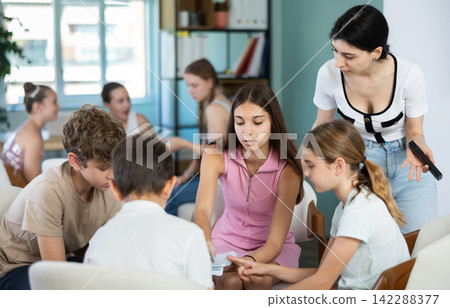 Two groups of children sitting in circle, discussing game tactics. Pioneer leader watch game Two groups of children sitting in circle, discussing game tactics. Pioneer leader watch game 142288377
