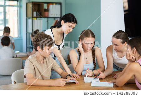 Teenagers discussing task at table in learning club Teenagers discussing task at table in learning club 142288398