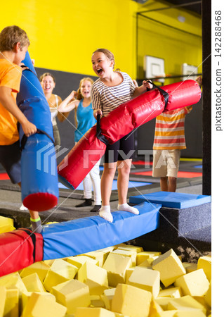 Children having funny wrestling by inflatable logs with his friends in amusement playground Children having funny wrestling by inflatable logs with his friends in amusement playground 142288468