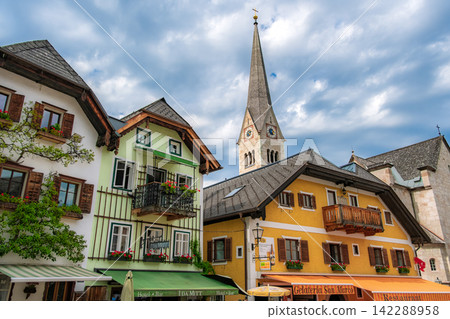 Hallstatt, Austria. Colorful houses in the market square and the spire of the Lutheran church standing in the background. Hallstatt, Austria. Colorful houses in the market square and the spire of the Lutheran church standing in the background. 142288958