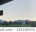 Serene alpine landscape with distant mountain silhouettes under soft twilight sky 142289103