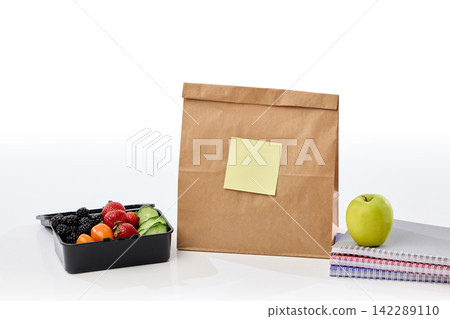 Healthy lunch box, apple and notebooks arranged around paper bag 142289110