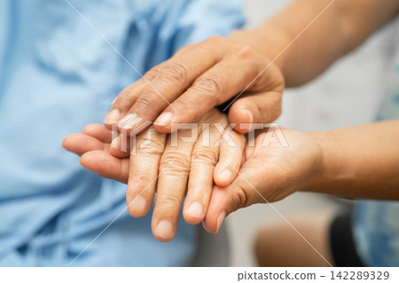 Caregiver holding hands Asian elderly woman patient, help and care in hospital. Caregiver holding hands Asian elderly woman patient, help and care in hospital. 142289329