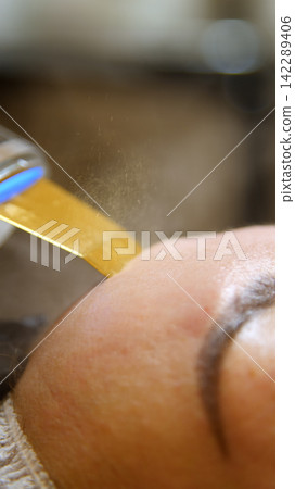 Kyiv, Ukraine - August 17, 2026: Professional beautician applying cleansing mask on female client's face. Injections of skin-lifting treatments. Mesotherapy. Close-up of female face during youth Kyiv, Ukraine - August 17, 2026: Professional beautician applying cleansing mask on female client's face. Injections of skin-lifting treatments. Mesotherapy. Close-up of female face during youth 142289406