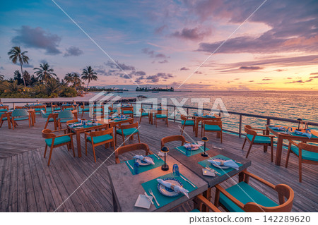 Gorgeous overwater dining deck glowing pastel dusk vivid azure Maldives lagoon terrace resort tables. Luxury honeymoon travel paradise scenic. Exotic couples getaway decor wallpaper Gorgeous overwater dining deck glowing pastel dusk vivid azure Maldives lagoon terrace resort tables. Luxury honeymoon travel paradise scenic. Exotic couples getaway decor wallpaper 142289620