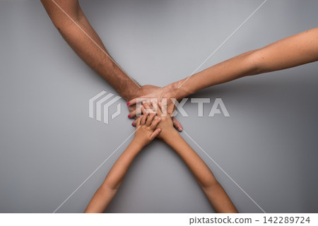 Family clasping hands in a teamwork concept 142289724