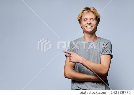 Portrait of smiling teenage boy pointing thumb at copy space 142289773