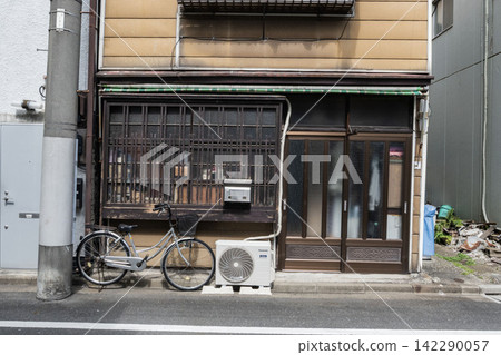 A traditional Japanese house full of signs of everyday life, with a bicycle and an air conditioner unit placed outside the eaves. A traditional Japanese house full of signs of everyday life, with a bicycle and an air conditioner unit placed outside the eaves. 142290057
