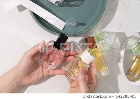 Handheld perfume bottle for fragrance demonstration on luxurious vanity setup Handheld perfume bottle for fragrance demonstration on luxurious vanity setup 142290403