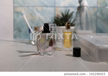 Clear glass perfume bottle with pink liquid on a marble bathroom vanity - premium fragrance display Clear glass perfume bottle with pink liquid on a marble bathroom vanity - premium fragrance display 142290425
